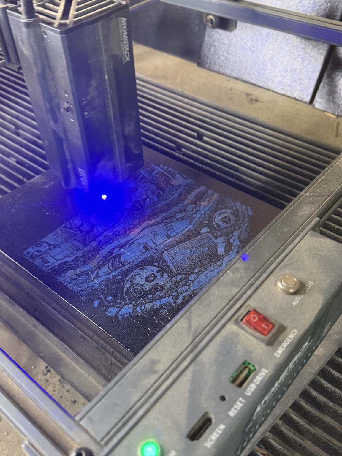 The laser engraver adding detailed artwork to a painted canvas