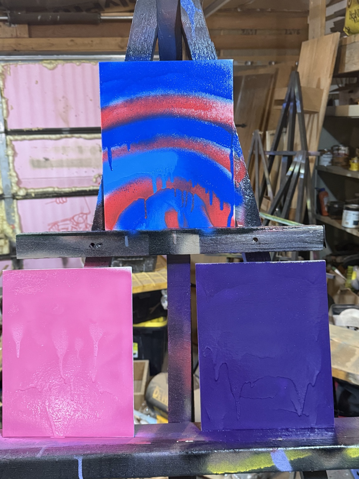 Colorful painted canvas panels on an easel in the TCJ spray paint area